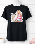 Short-sleeved T-shirt featuring a design of a girl in a pink sweater on a pier, deep in thought while drinking a cup of coffee.