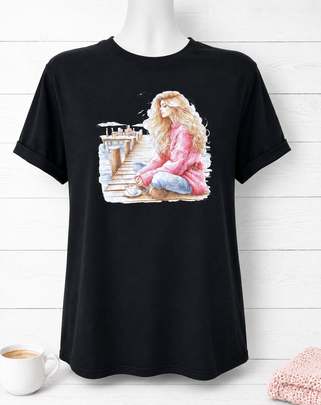 Short-sleeved T-shirt featuring a design of a girl in a pink sweater on a pier, deep in thought while drinking a cup of coffee.